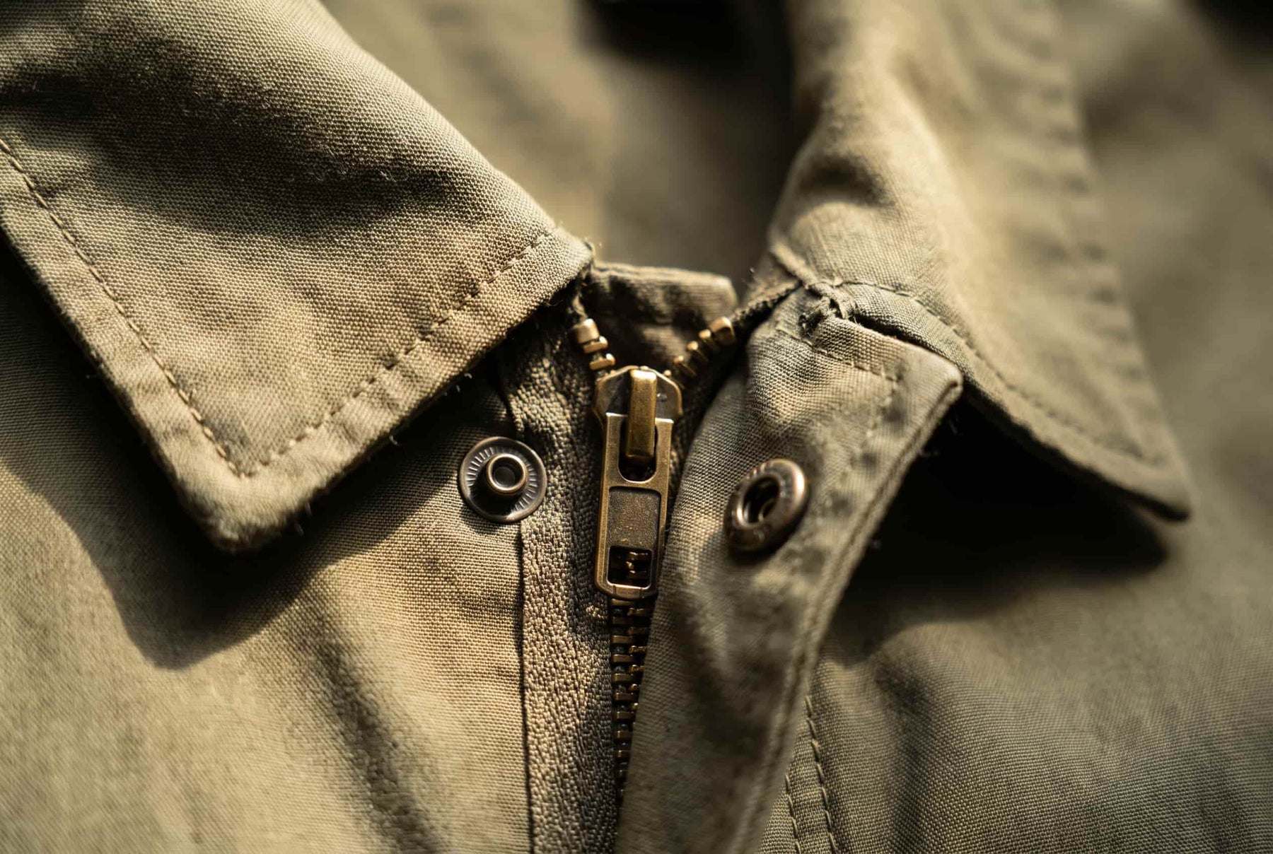 DETAIL 02 — collar + zip pull macro · raking sidelight on the weave